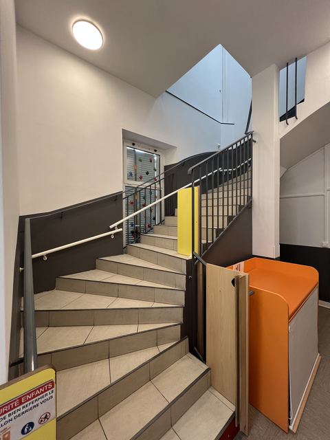 Cage d'escalier de creche repeinte avec rampe metallique et panneaux de securite enfants