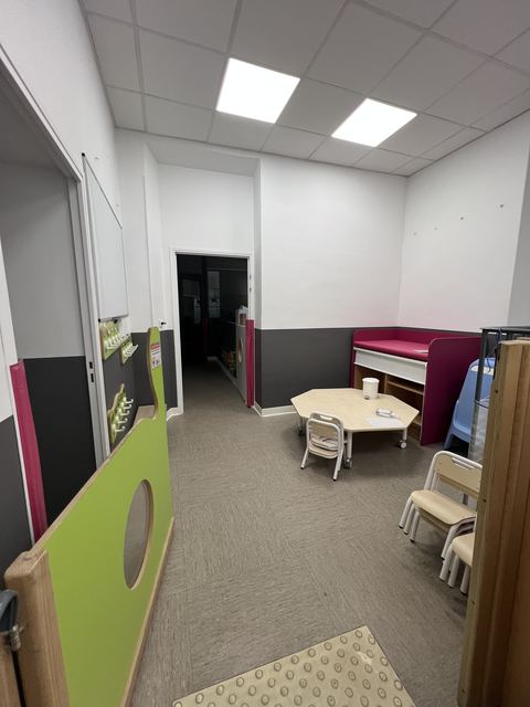Couloir de creche repeint en blanc avec casiers rouges et grandes fenetres