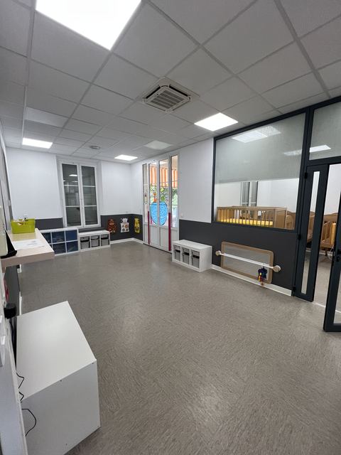 Couloir de creche fraichement peint avec mobilier bas et fenetres colorees